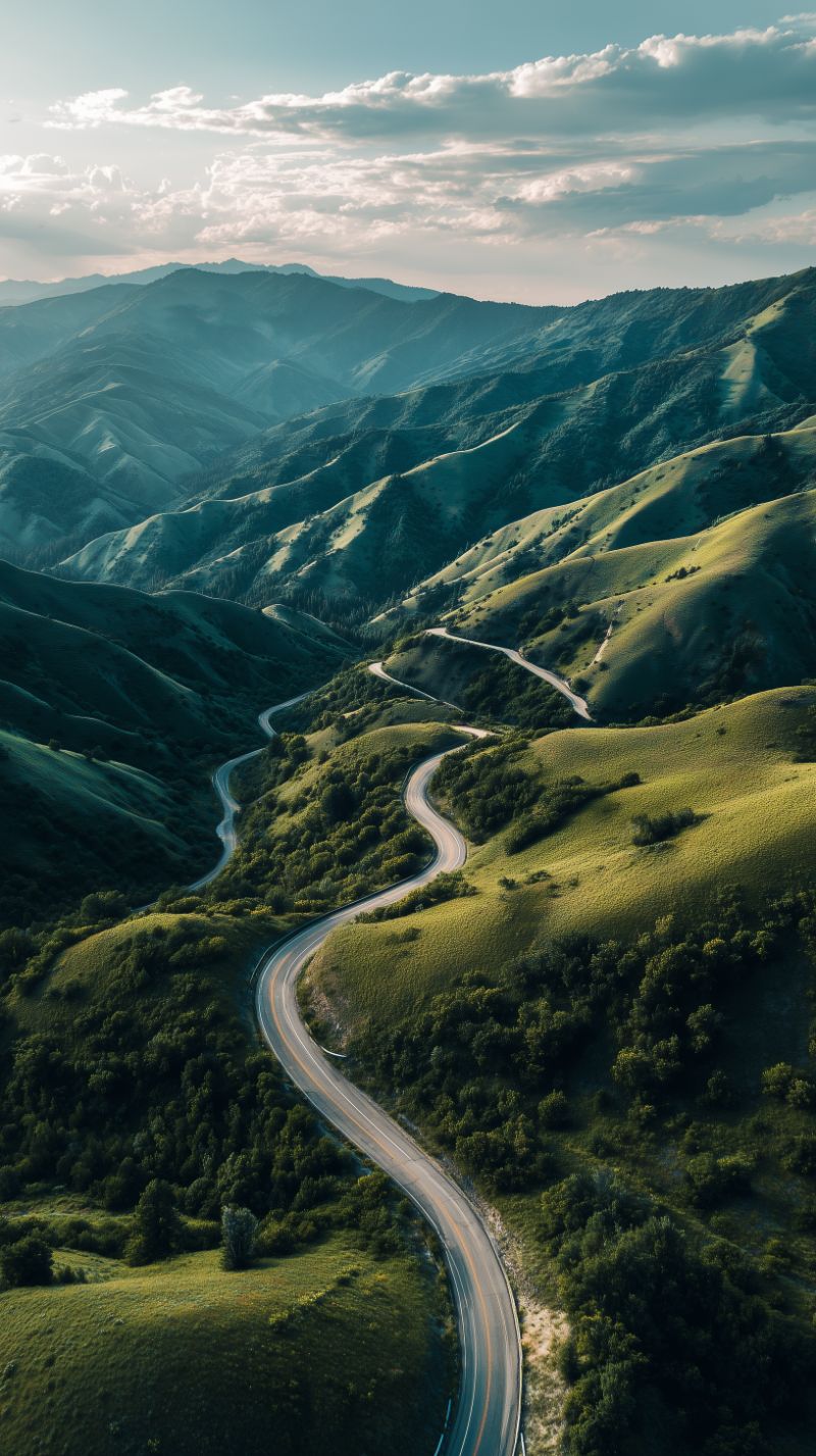 Aerial winding road through emerald mountains